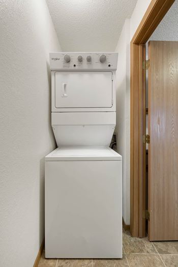 A white dishwasher is in a narrow space between a wall and a door.